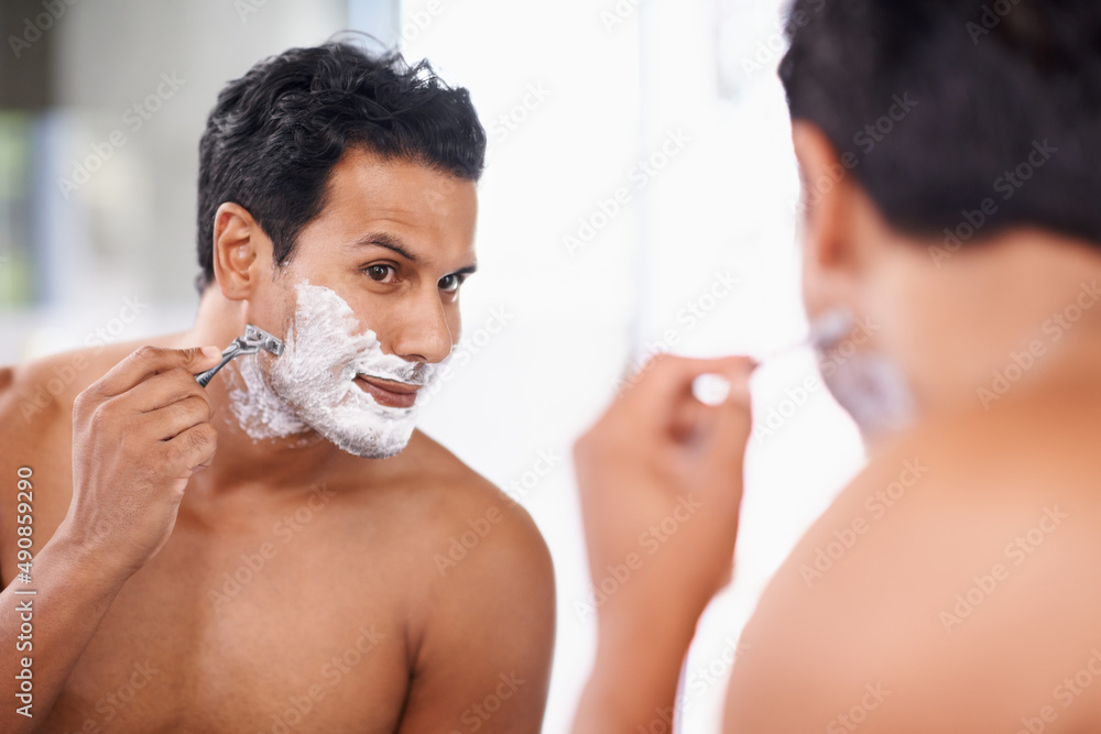 The ladies love a smooth face. A handsome young man shaving in the bathroom.