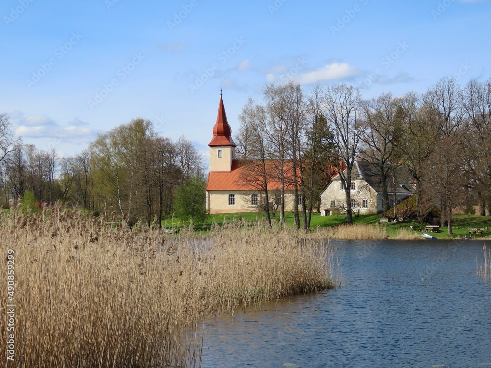 Araishi Evangelical Lutheran Church seen from over the lake on a sunny spring day. Latvia, Gauja National Park in Cesis region