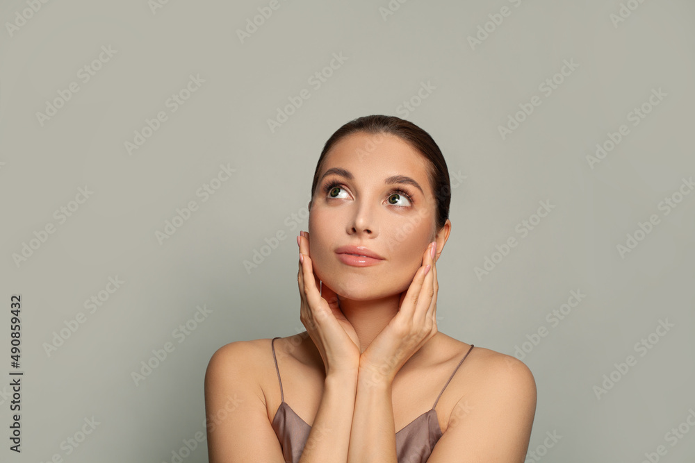 Pretty young woman face. Healthy woman looks to the side on gray background Pretty young woman face. Healthy woman looks to the side on gray background