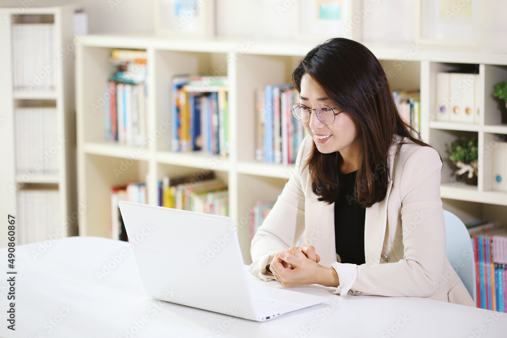 Modern office worker woman smiling brightly at home or office and working from home via internet online on laptop Modern office worker woman smiling brightly at home or office and working from home via internet online on laptop