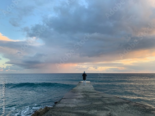 Small human silhouette by the sea, evening time 