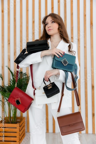 A few colorful stylish handbags. fashionable women's leather clutch bag. Traditional women's clutch bag with gold fittings made of fine colored leather. The girl in the frame. 