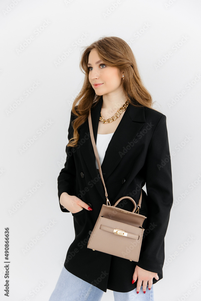 Girl holding her handbag, close-up. Small fashionable women's leather clutch bag with fabric strap in shoe tone. Girl's Traditional clutch bag with brooch. handbag made of fine coloured genuine leathe Girl holding her handbag, close-up. Small fashionable women's leather clutch bag with fabric strap in shoe tone. Girl's Traditional clutch bag with brooch. handbag made of fine coloured genuine leathe