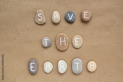 Save the Earth letters from pebbles on craft paper background. Ecological, eco friendly, zero waste, nature concept. Earth Day flatly top view postcard, banner.