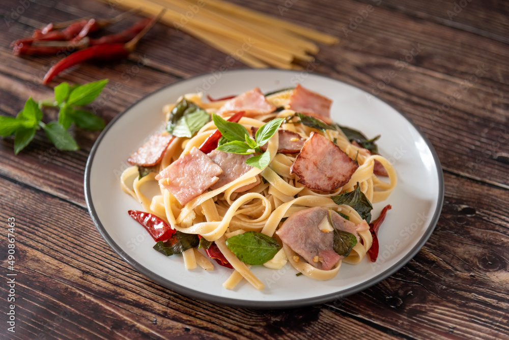 Stir Fried Spicy Spaghetti with ham on wooden background as Thai and Italian fusion food Stir Fried Spicy Spaghetti with ham on wooden background as Thai and Italian fusion food