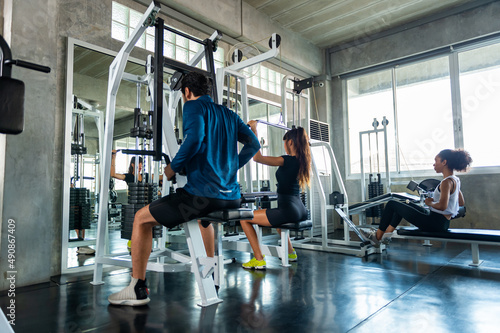 Healthy athletic man and woman in sportswear workout exercise weight lifting together at fitness gym. Male and female do body building weight training at sport club. Health care motivation concept
