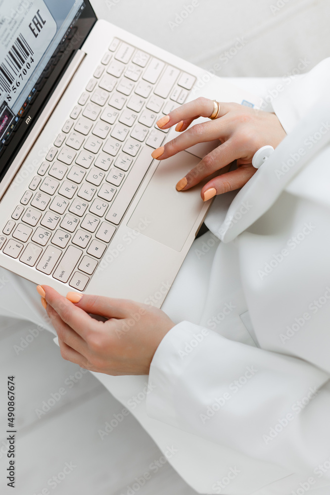 A businesswoman in a white suit works on her gold laptop. a blonde girl sits on the sofa and takes notes on her laptop. A businesswoman in a white suit works on her gold laptop. a blonde girl sits on the sofa and takes notes on her laptop.