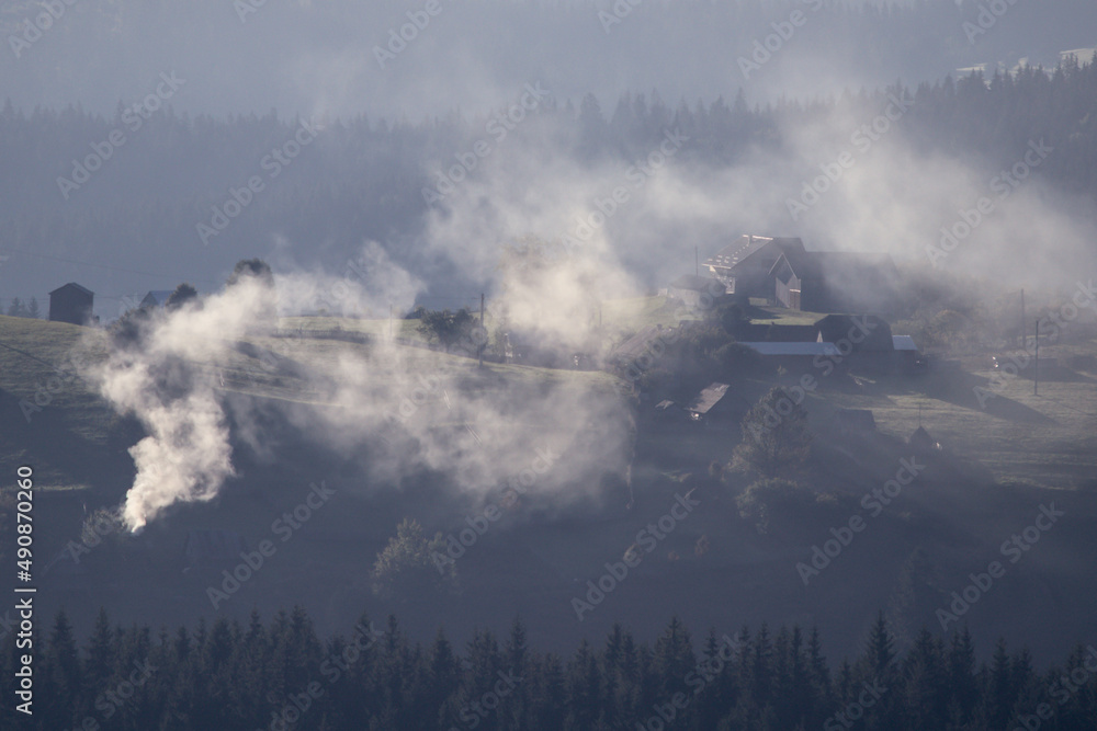 Moutain landscape. Lot of smoke coming out of a chimney from an old house in Lupcina, Romania