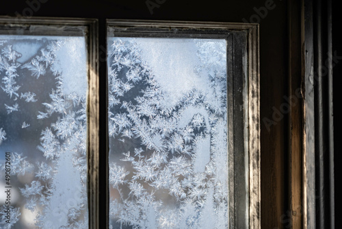 Old fashion window covered in frost with morning light shining thru the glass  dark contrast inside  shadows and light.