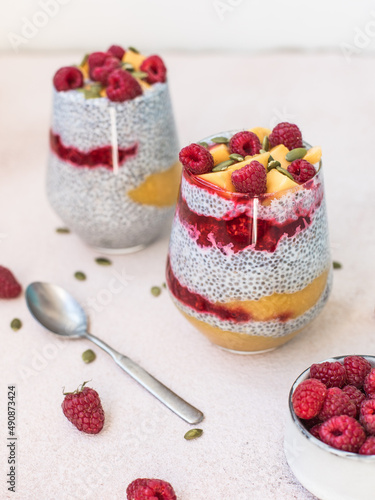 Healthy vegan chia pudding with mango and raspberries sauce with with mango pieces, pumpkin seeds and raspberries 