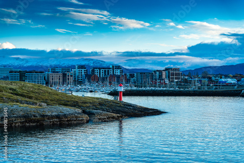 Hafeneinfahrt von Bodø mit Leuchtfeuer und Jachthafen, Segelschiffe und Hochhausquartier im Abendlicht. Halo in der Wolke. Abend in Norwegen mit Schiffleitsystem photo