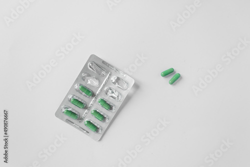 Fototapet Silver blister with supplements and vitamins in green capsules on white background