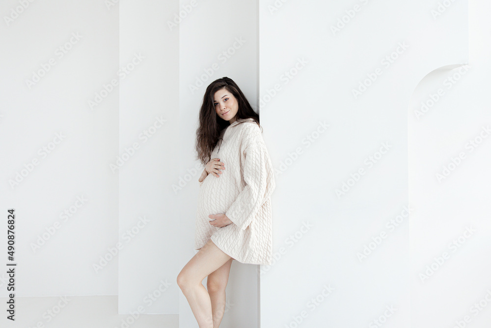Pregnant brunette girl in an oversized knitted sweater Pregnant brunette girl in an oversized knitted sweater