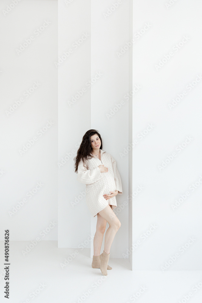 Pregnant brunette girl in an oversized knitted sweater Pregnant brunette girl in an oversized knitted sweater