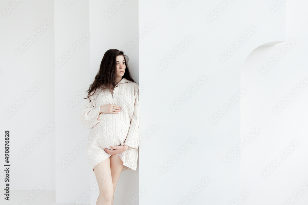 Pregnant brunette girl in an oversized knitted sweater Pregnant brunette girl in an oversized knitted sweater