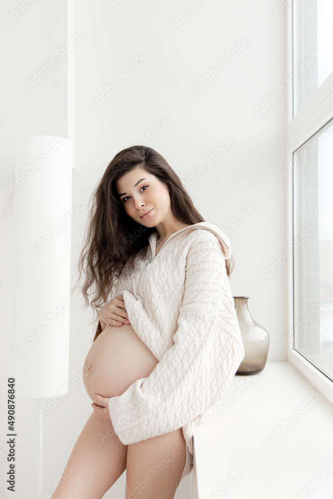 Pregnant brunette girl in an oversized knitted sweater Pregnant brunette girl in an oversized knitted sweater