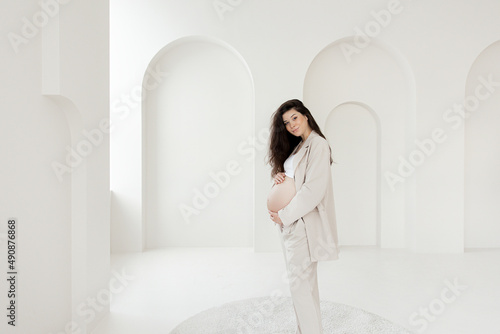 Stylish pregnant brunette girl with beige trouser suit