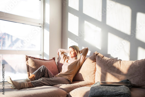 Relaxed middle-aged woman is resting at home sitting on the couch photo