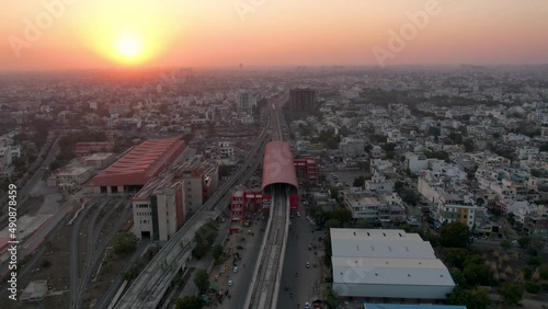 hyperlapse shot at dusk sunset flying over elevated metro track with busy road underneath and metro shed on the side and densely packed houses showing Indian city jaipur lucknow photo