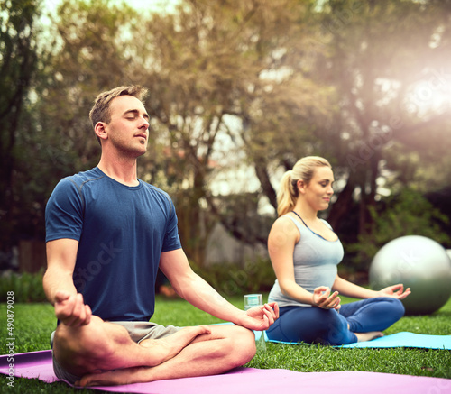 Gaining a healthier physical and mental wellbeing. Shot of a young couple practising yoga together outdoors.