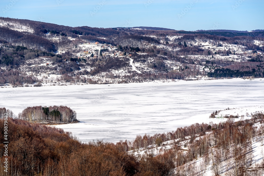 Winter landscape by the frozen lake with hills in the background background. Frozen Lake on a cold winter day