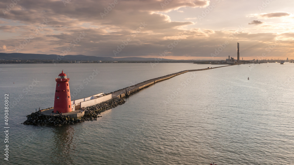 Aerial view of Poolbeg Lighthouse the famous red landmark in Dublin Harbor Ireland seen by drone at sunset