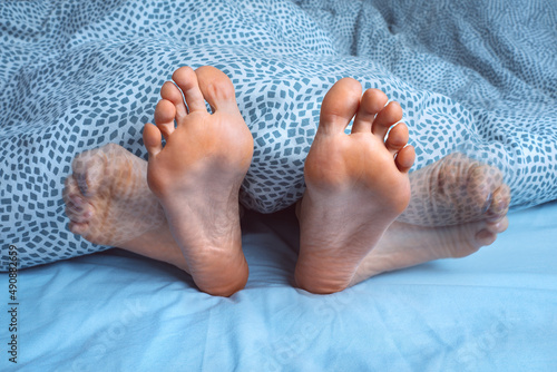 Woman suffering from foot cramps, leg cramps or muscular spasm while sleeping. Feet pain or feet ache at night. Restless legs syndrome photo