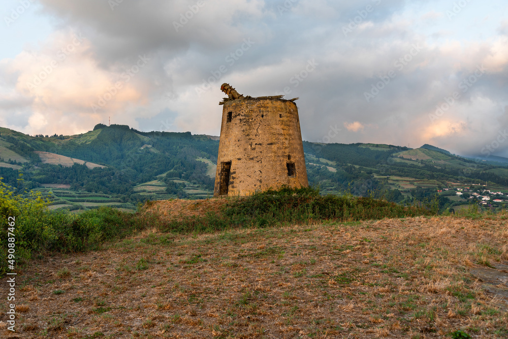 Natural landscape at sunset with old mill on the island of Sao Miguel, Azores, Portugal. Outdoors with no people and the sea in the background.