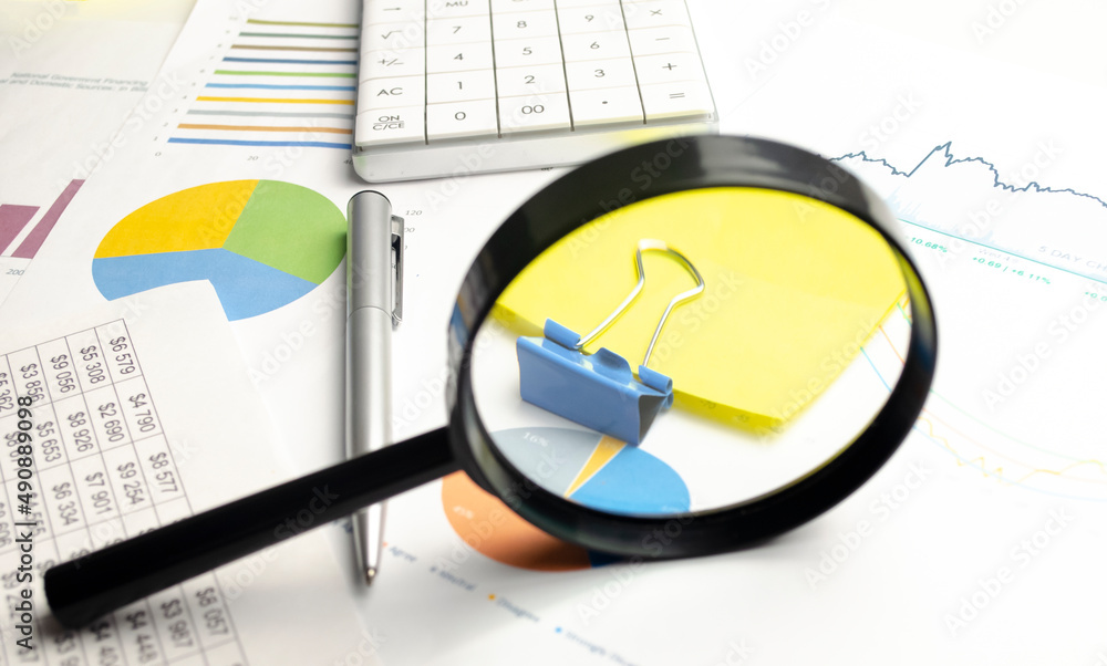 charts and graphs with magnifying glass and pencil, calculator