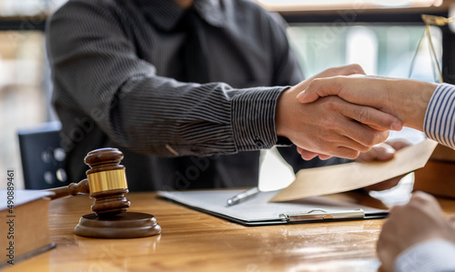 Lawyers shake hands with clients who come to testify in the case of embezzlement from business partners who jointly invest in the business. The concept of hiring a lawyer for legal proceedings.