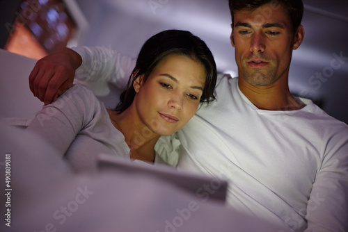 Cosy time has arrived. Cropped shot of a couple watching movies on a digital tablet while sitting in bed.
