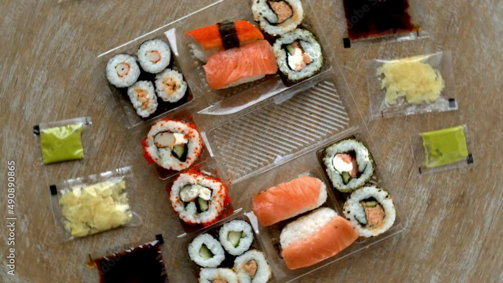 Take away sushi in plastic box top view. Sushi food with soy sauce, wasabi paste and pickled ginger in bags. Take away sushi in plastic box top view. Sushi food with soy sauce, wasabi paste and pickled ginger in bags.
