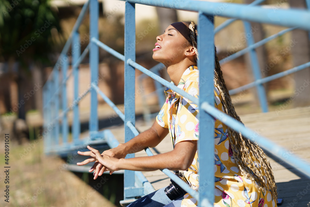 Black Girl With Braids Sitting On A Bridge Enjoying The Sun On Her Face