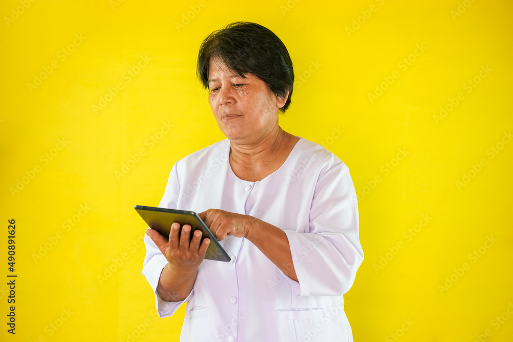 elderly woman using ipad isolated on yellow background elderly woman using ipad isolated on yellow background