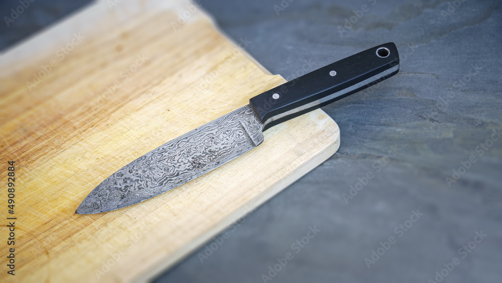 Damascus steel knife on a wooden board Damascus steel knife on a wooden board