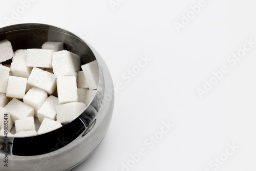 a lot of cubes of white refined sugar in a metal sugar bowl top view close-up place for text