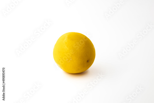 One whole citrus fruit a hybrid of orange and lemon in light orange color with shadow on a white background
