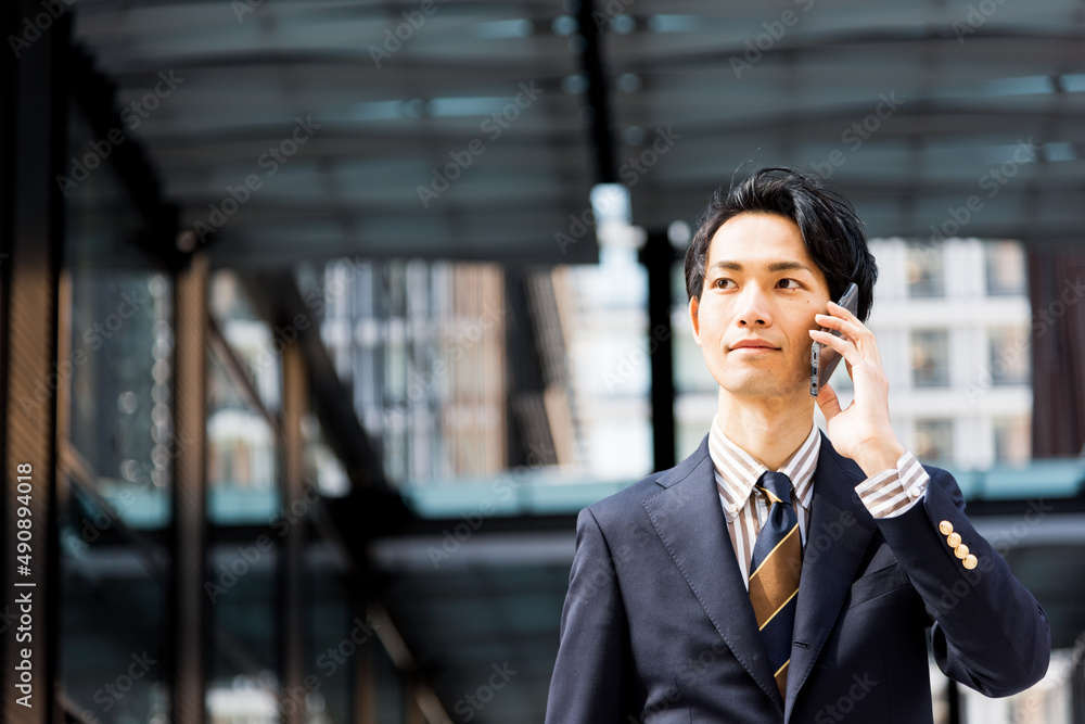 オフィス街でスマートフォンを使うビジネスマン オフィス街でスマートフォンを使うビジネスマン