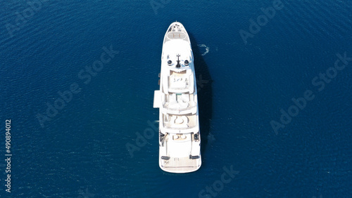 Aerial drone top down photo of large yacht with wooden deck anchored in Aegean island deep blue sea
