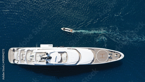 Aerial drone top down photo of large yacht with wooden deck anchored in Aegean island deep blue sea