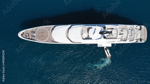 Aerial drone top down photo of large yacht with wooden deck anchored in Aegean island deep blue sea © aerial-drone