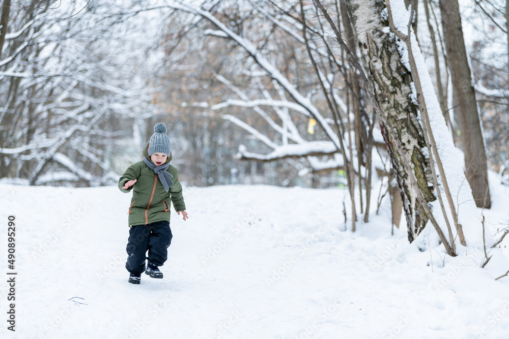 Child running among the trees on snow in winter.