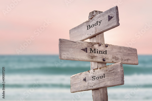 body mind soul text quote written on wooden signpost by the sea. Positive pink turqoise pastel theme.