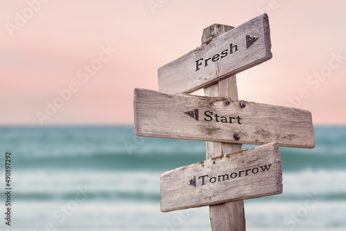 fresh start tomorrow text quote written on wooden signpost by the sea. Positive pink turqoise pastel theme.