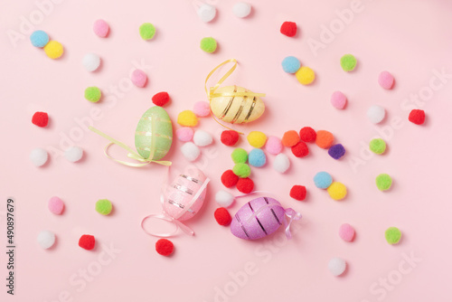 Easter composition of decorative shiny eggs and fluffy balls on a pink background. Background for your project for the holiday happy easter