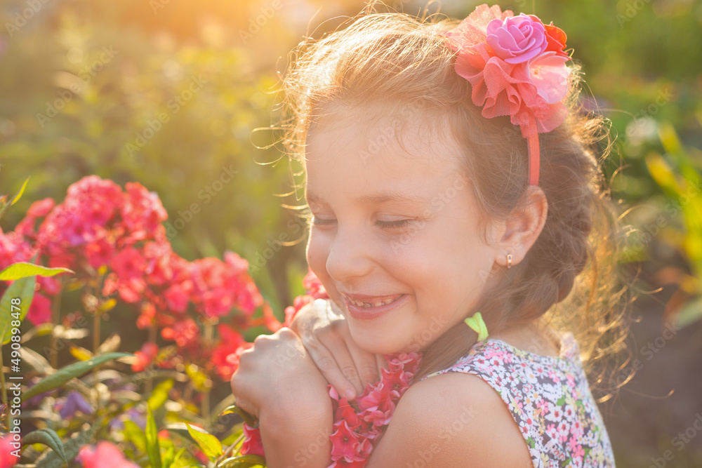 In the rays of the setting sun, the girl embraces red phlox In the rays of the setting sun, the girl embraces red phlox