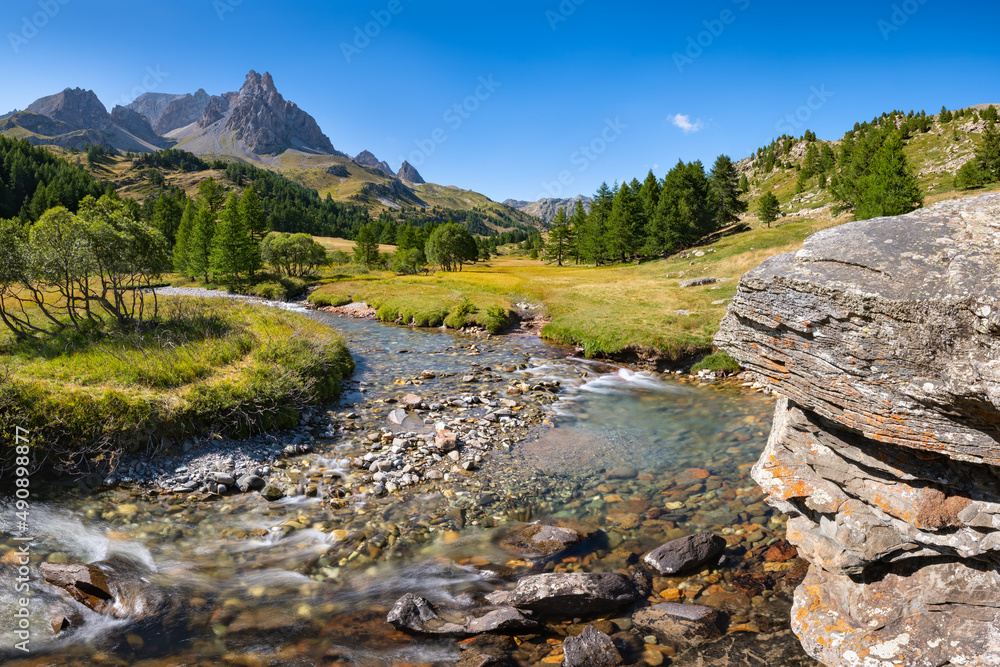 La Claree river in Summer with Main de Crepin peak in the Cerces Massif mountains. Claree Valley (Laval) in Hautes Alpes (Alps), France La Claree river in Summer with Main de Crepin peak in the Cerces Massif mountains. Claree Valley (Laval) in Hautes Alpes (Alps), France