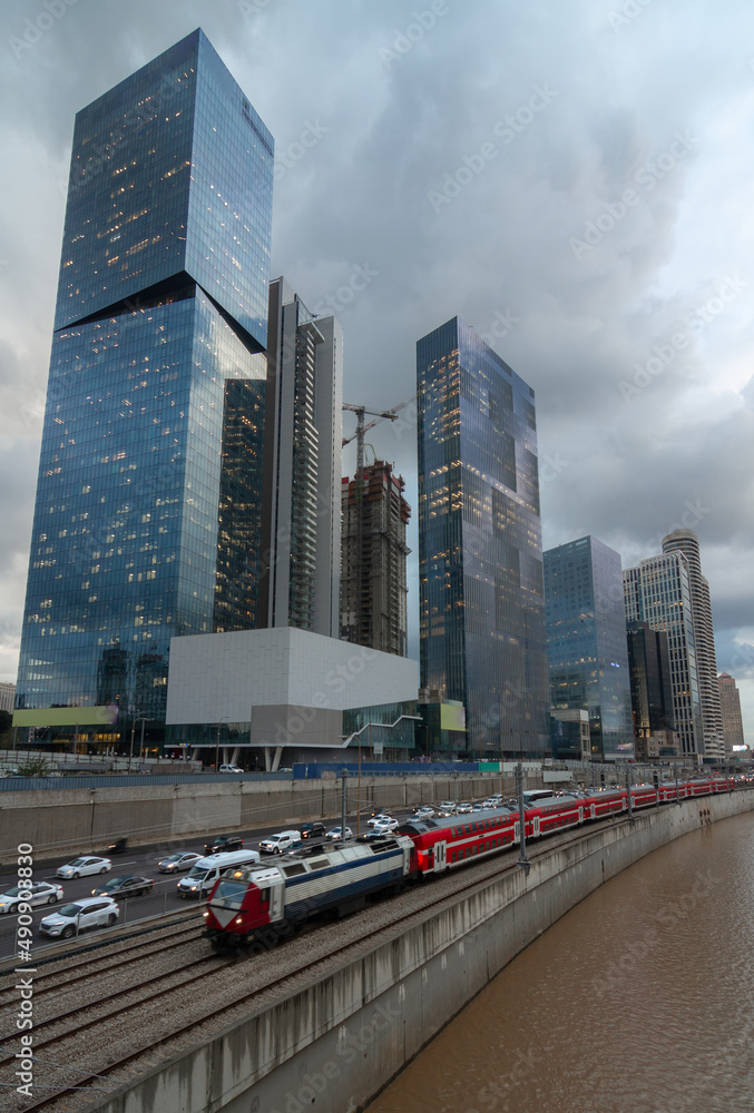 Cloudy gloomy Tel Aviv city before the sunset. Modern glass skyscrapers and automobile Ayalon highway. Electric train Cloudy gloomy Tel Aviv city before the sunset. Modern glass skyscrapers and automobile Ayalon highway. Electric train