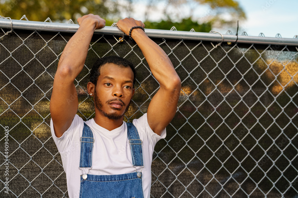 Man with arms above head leaning on a fence Man with arms above head leaning on a fence