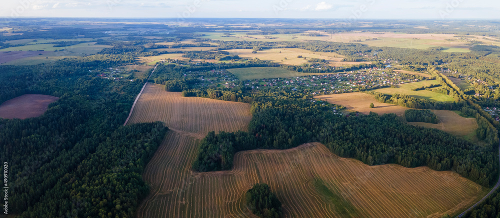 Aerial panorama of autumn farmlands with small village. Beautiful rural landscape with harvested from the field.